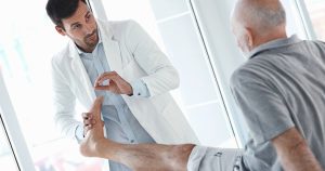 doctor examining an ankle of a senior gentleman
