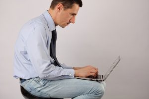 Business man sitting using laptop with poor posture