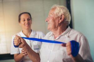 Senior man doing exercises using a strap to extend and strenthen her neck and shoulder muscles