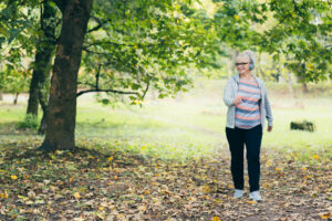 Beautiful woman, senior, running in headphones, walking in the park, playing sports